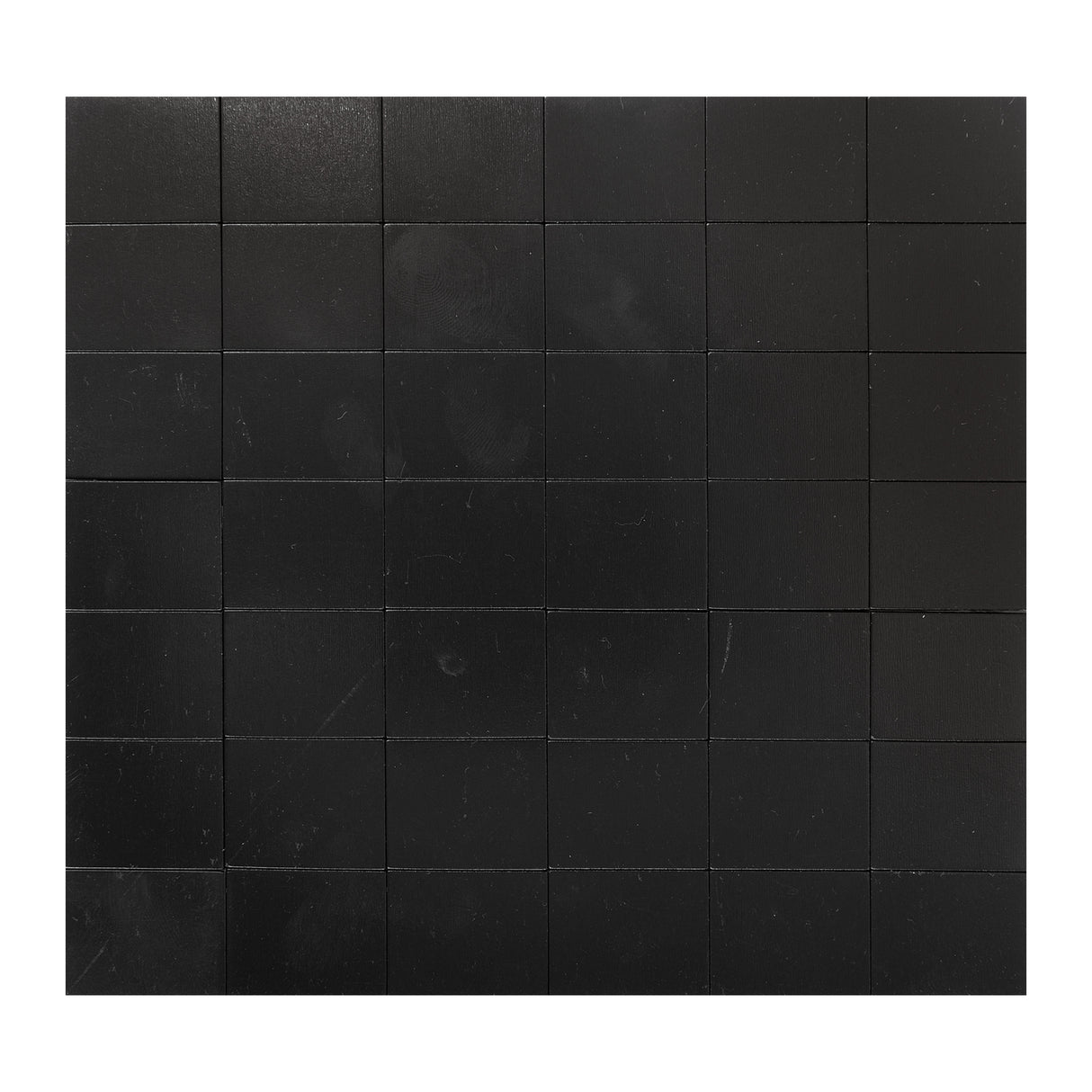 A grid of Zart Adhesive Magnets arranged in evenly spaced rows and columns, filling the frame from edge to edge. Each square is matte black with a faint woodgrain-like texture, separated by thin visible seams between the tiles.