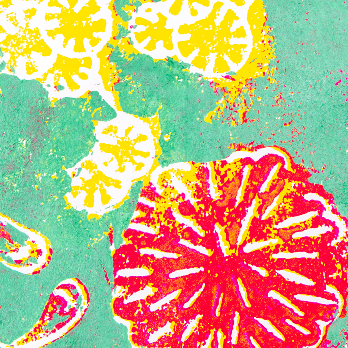 Close-up of a multi-colour print foam artwork showing layered yellow, green and bright pink ink. Etched floral and circular shapes appear in white negative space, with textured ink coverage and visible grain. The image highlights colour layering and reduction-style printing using print foam.