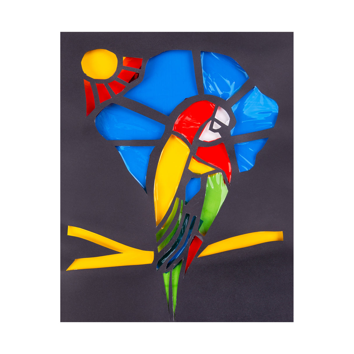 Parrot artwork created using cut coloured cellophane pieces mounted onto black card, forming a stained-glass style design with bold shapes. Bright yellow, red, blue and green translucent sections allow light to pass through for vibrant visual impact.