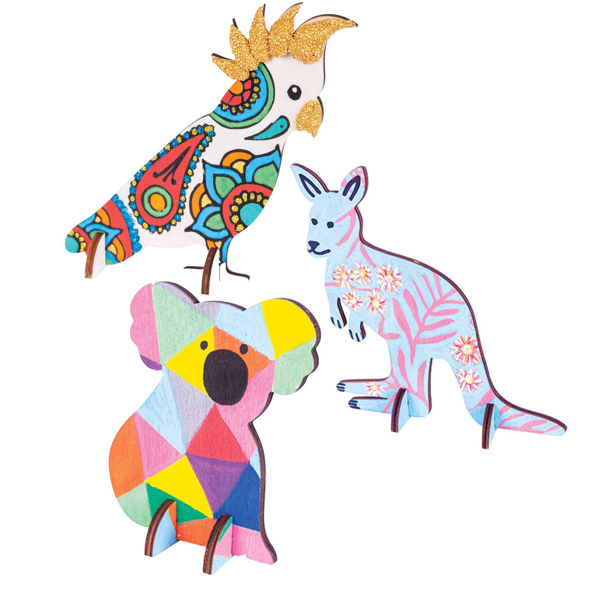 Three Zart Wooden Standing Australian Animals decorated with intricate patterned designs: a cockatoo painted in colourful paisley and mandala motifs with a gold glitter crest, a pale blue kangaroo detailed with pink native wattle flowers and fern leaves, and a koala covered in a rainbow geometric triangle pattern.