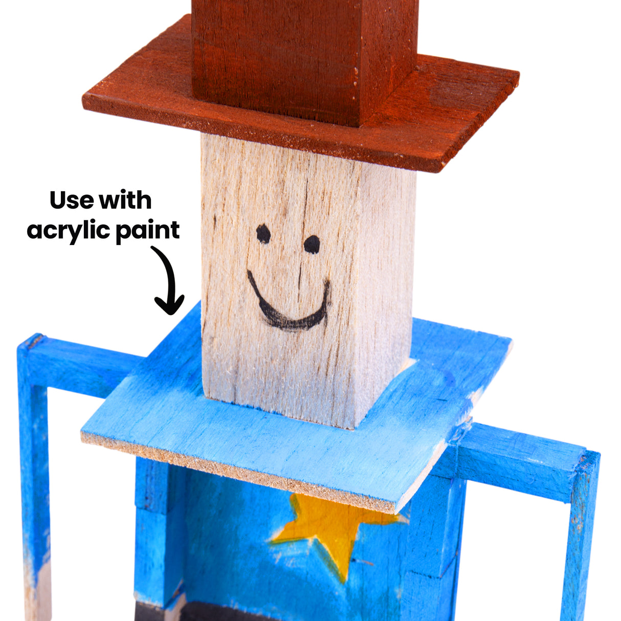 Close-up of painted balsa wood sheriff figure highlighting surface texture and paint application. Blue painted areas contrast with exposed pale wood grain on the face. Edges appear soft and slightly porous. Annotation text reads “Use with acrylic paint” with arrow pointing to painted section.