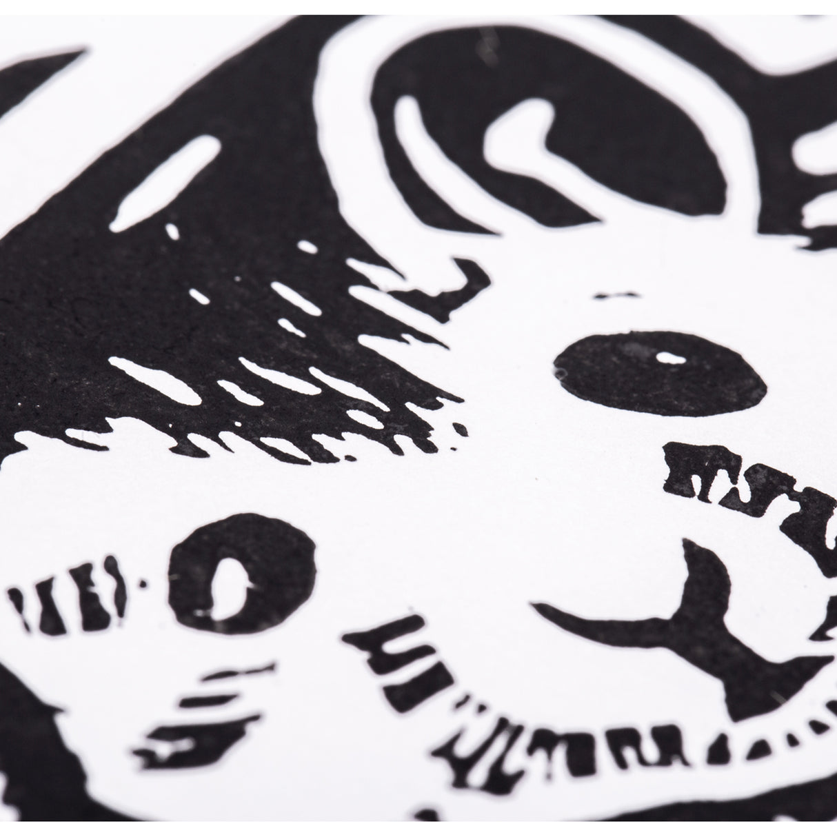Close-up of the printed mouse face in high-contrast black ink on white paper. Solid black areas define the eye, ear and fur, while small white carved marks create texture within the dark shapes. Edges appear crisp and clearly defined.