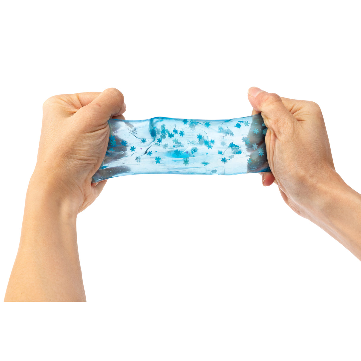 Two hands stretch a translucent blue sensory jelly cube filled with suspended turquoise star-shaped confetti pieces. The flexible, gel-like material demonstrates its squeezable, tactile properties. The Sensory Sprouts Jelly Cube features swirling blue tones and scattered decorative elements throughout its clear, squishy texture, ideal for sensory play and exploration.
