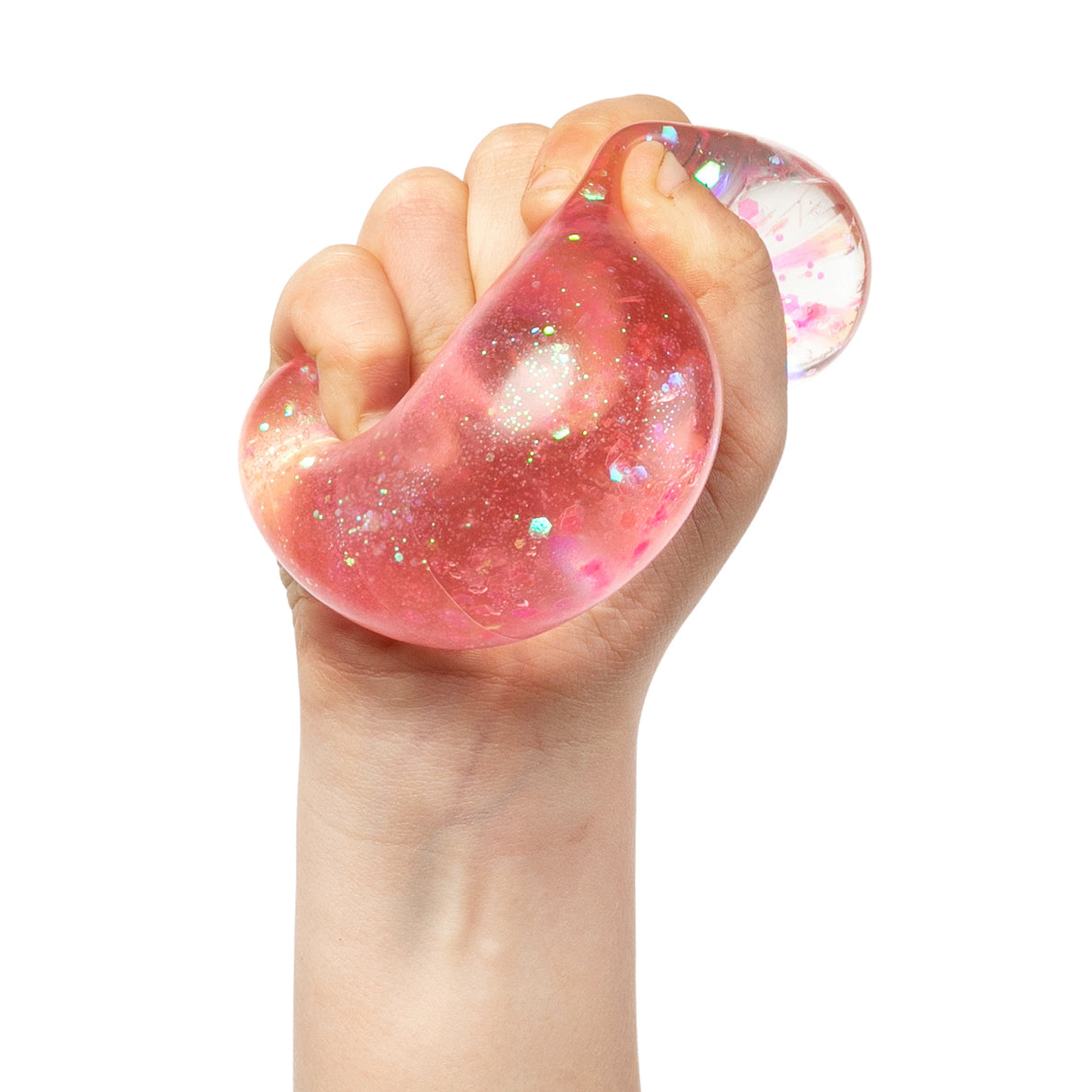 A hand squeezing a translucent pink sensory ball filled with iridescent glitter and holographic confetti, demonstrating the stretchy, tactile nature of Sensory Sprouts Stretch & Sparkle Shapes. The malleable material shows light reflecting through its sparkly interior, highlighting its stress-relief and sensory play qualities against a clean white background.