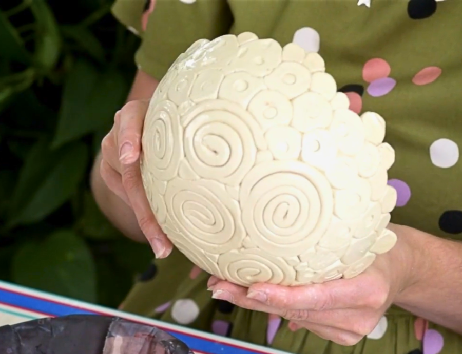 Zart Education Professional Learning The Essentials of Clay image showing hands holding a rounded ceramic vessel covered with layered circular and spiral clay elements. The pale cream-coloured surface features raised textures and repeating patterns, creating a richly detailed sculptural appearance.