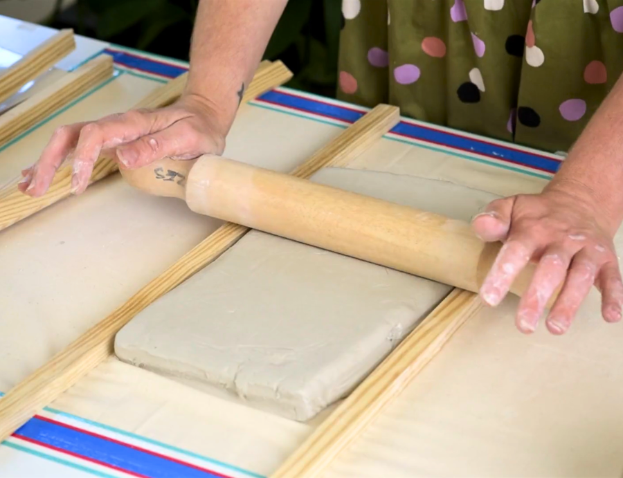 Zart Education Professional Learning The Essentials of Clay image showing hands using a wooden rolling pin to flatten a pale grey clay slab between timber guide strips on a tabletop. The clay surface appears smooth and even, with tools and materials partially visible around the workspace.