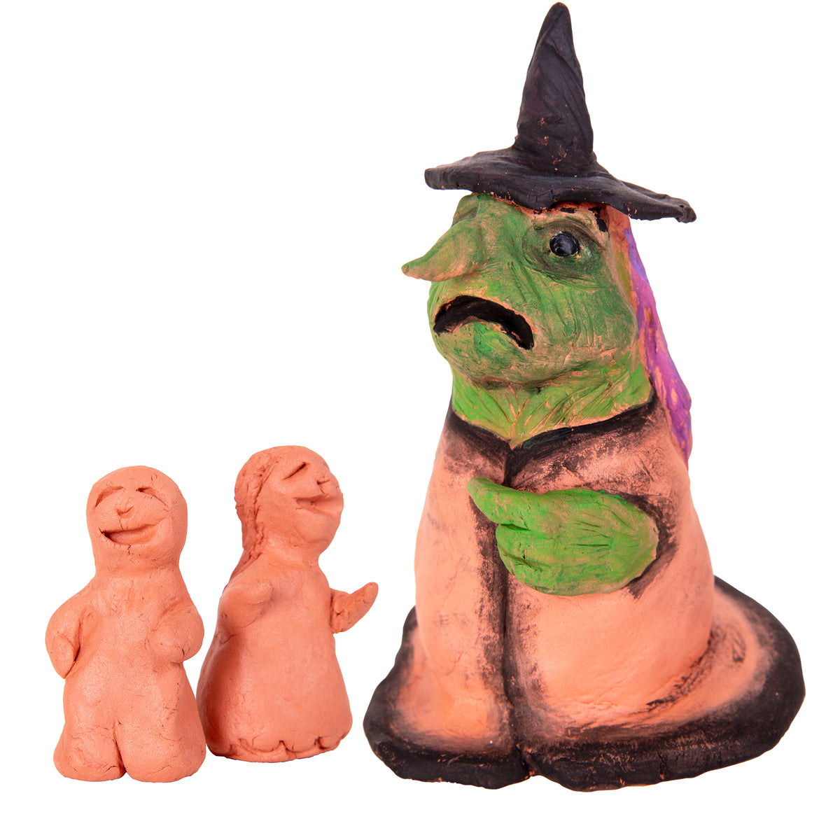 Two small unpainted terracotta figures with simple rounded bodies and faces, standing beside a larger sculpted terracotta figure of a witch painted with a green face, purple-trimmed cloak and a tall black hat.