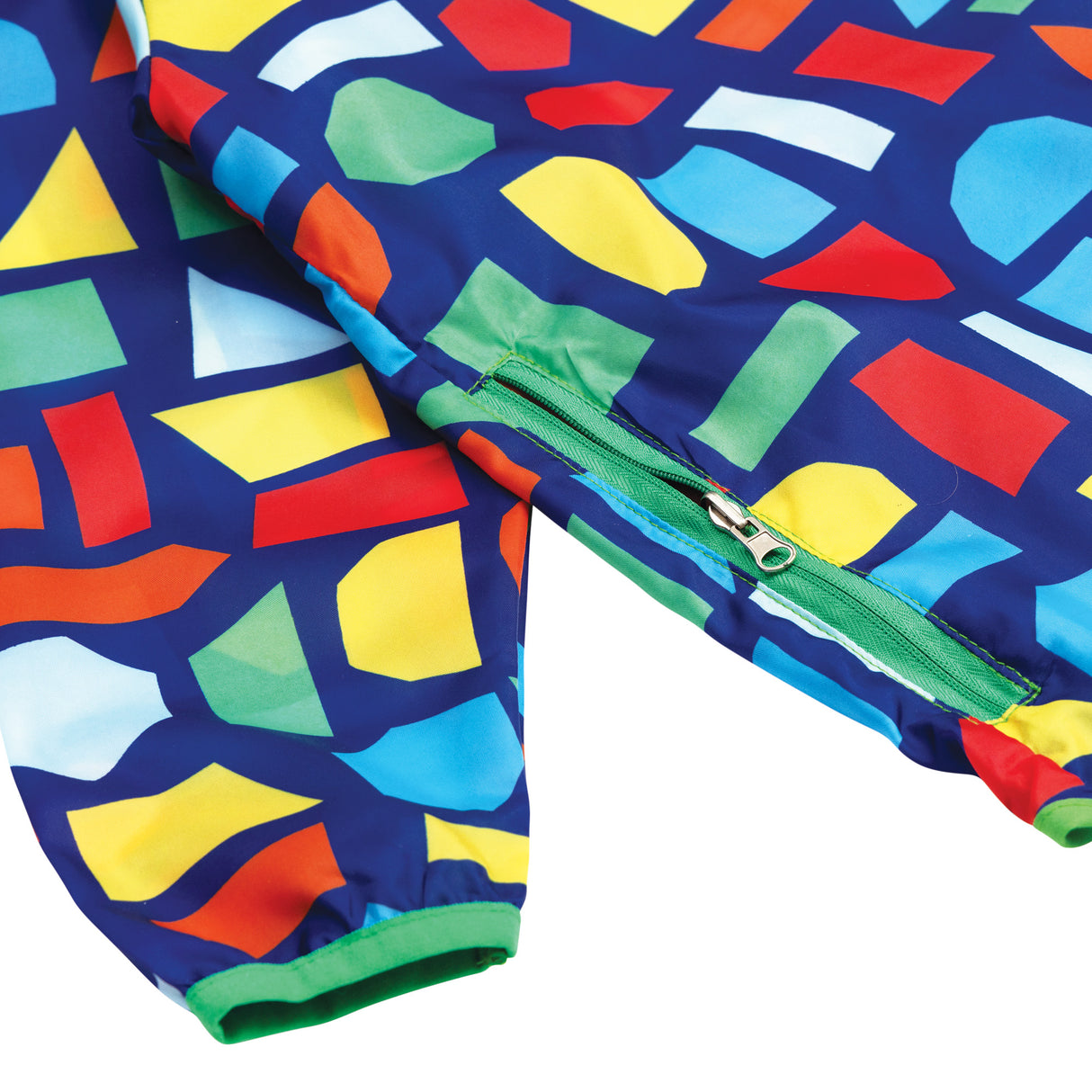 Vibrant navy art smock with colourful geometric shapes in yellow, red, orange, green, and blue. Features a green zip-up pouch pocket on the front and elasticated green cuffs. The Spencil Art Smock in Medium/Large size is shown draped to display the bold, contemporary pattern.