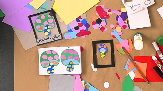 A fan-folded zine displaying a repeated mushroom collage design, alongside a framed version labelled "creative flow", from Zart Education On Demand's Mushroom Collage activity. Colourful paper scraps, punched dots, and craft tools surround the display, showing layered green, pink, blue, and yellow shapes creating a vibrant, playful mushroom motif.