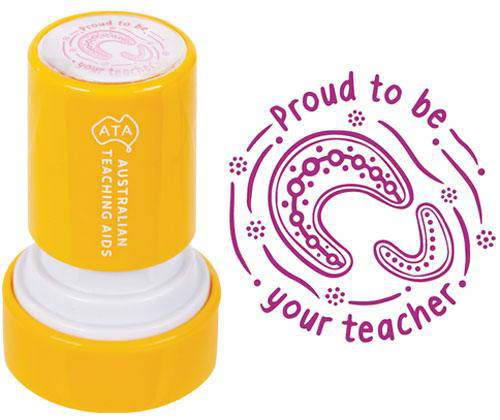 Bright yellow self-inking stamp showing Aboriginal dot art design on top surface, positioned next to purple stamped impression reading "Proud to be your teacher" with decorative Indigenous-style patterns and dots forming a curved design around the text.