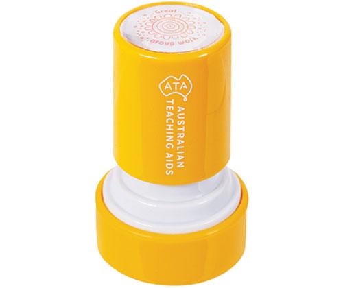 Bright yellow self-inking stamp with white cap removed showing circular stamp pad. The Australian Teaching Aids branded Country Connections Stamps features a spiral pattern design visible on the top lid, ideal for creating repetitive patterns in classroom art activities.