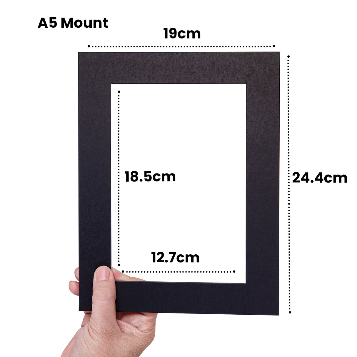 Hand holding a black A5 mount board with white matting, displaying dimension annotations: A5 Mount 19cm width, 24.4cm height, with inner window measuring 18.5cm by 12.7cm. The textured black frame surrounds a clean white aperture, ideal for presenting and framing artwork.