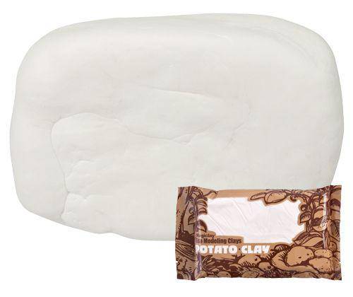 White rectangular block of Magiclay Porcelain/Potato Clay with smooth, pliable texture and rounded edges. A brown decorative label reading "Magiclay Porcelain/Potato Clay" sits in front, featuring an ornate floral border design with leaves and vines in a copper tone.