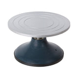Pottery turning wheel with light grey circular steel top featuring concentric guide rings for centring work, mounted on a dark teal weighted base with ball-bearing mechanism for smooth 360-degree rotation, ideal for hand-building, decorating and sculpting ceramic projects.