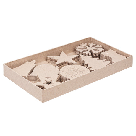 An open cardboard tray filled with assorted unpainted Zart Papier-mache Christmas decorations in natural kraft brown, including stacks of stars, snowflakes, trees, baubles, and a stocking shape, ready for decorating.