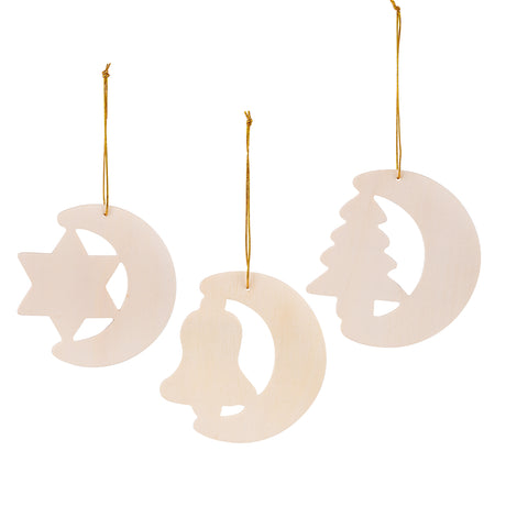 Three plain Zart Wooden Christmas Shapes hang by gold cord: a crescent moon with a star cut-out, a crescent moon with a bell cut-out, and a crescent moon with a tree cut-out. Each shows the natural plywood finish, ready for painting or decorating.
