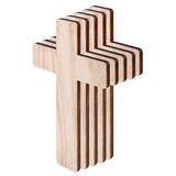 Stacked wooden cross shapes shown fanned to reveal thickness and layered edges. Smooth pale timber surfaces contrast with darker burnt edges. Rounded corners soften the form. Multiple identical pieces aligned, suggesting craft blanks ready for decorating, painting, or mosaic projects in classroom or studio use.