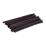A loose bundle of natural willow charcoal sticks arranged diagonally against a white background. The slim, irregular black sticks vary slightly in thickness and length, with matte charcoal surfaces and uneven natural ends, showing the organic, rustic character of the drawing material.