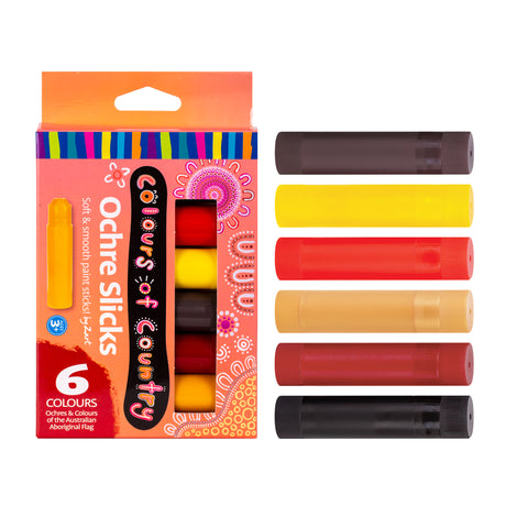 Zart Colours of Country Ochre Slicks packaging shown beside all six sticks laid flat, in dark brown, yellow, red, tan, dark red and black. The peach box has a rainbow-striped top band, dot-art lettering, a cut-out window revealing stacked colours inside, and a single yellow stick pictured at left.