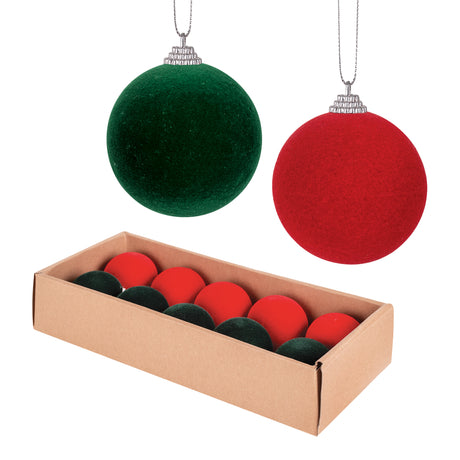 Two Zart Flocked Baubles in velvety green and red hang by silver cord loops, showing their soft flocked texture. Below, a kraft cardboard box holds a row of matching red and green baubles nestled together, illustrating how the pack of 10 is packaged for sale.