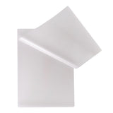 Two translucent Zart Laminating Pouches overlap against a pale grey background. One pouch is partially lifted to reveal the flexible frosted plastic surface, rounded corners, and smooth semi-matte finish. The layered sheets appear lightweight with subtle soft shadows and gentle curved edges.