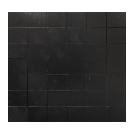 A grid of Zart Adhesive Magnets arranged in evenly spaced rows and columns, filling the frame from edge to edge. Each square is matte black with a faint woodgrain-like texture, separated by thin visible seams between the tiles.