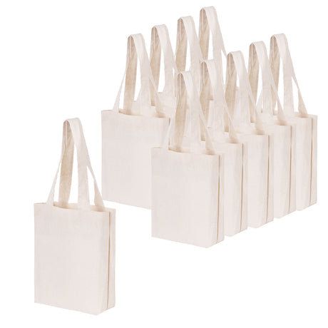 A group of ten plain, natural-toned Zart Calico Bags arranged together, each with two long handles and a flat rectangular body. One bag sits separately at the front, facing forward, while the remaining nine are grouped behind it at a slight angle.