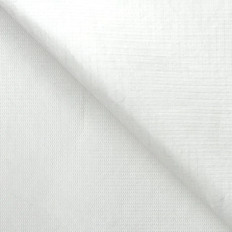 A sheet of white Tyvek material folded diagonally across itself against a white background. The surface shows a subtle woven texture with a faint grid and dotted pattern pressed into it. The lightweight sheet has a soft matte finish, with gentle creasing where it folds.