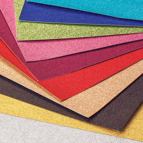Zart Glitter Iron-On Sheets fanned out to reveal a vivid range of colours, including pink, teal, blue, green, magenta, red, gold, bronze, black, yellow and silver. Each sheet has a fine, densely packed glitter finish with a soft sheen, showcasing the full assorted colour palette.