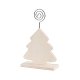 A plain, unpainted Zart Photo Holder Tree in a Christmas tree silhouette, mounted upright on a small rectangular wooden base. A silver spiral wire clip curls upward from the tip of the tree, ready to hold a photo or note between its curled loop and hooked end.