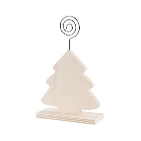 A plain, unpainted Zart Photo Holder Tree in a Christmas tree silhouette, mounted upright on a small rectangular wooden base. A silver spiral wire clip curls upward from the tip of the tree, ready to hold a photo or note between its curled loop and hooked end.