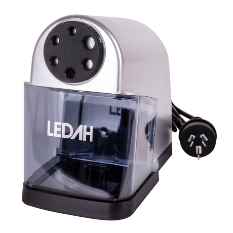 The Ledah Electric Pencil Sharpener is shown against a pale background with a silver and black body, clear removable shavings tray and attached Australian power plug. The front features six sharpening size holes, while the compact desktop design suits classrooms, studios and office environments.