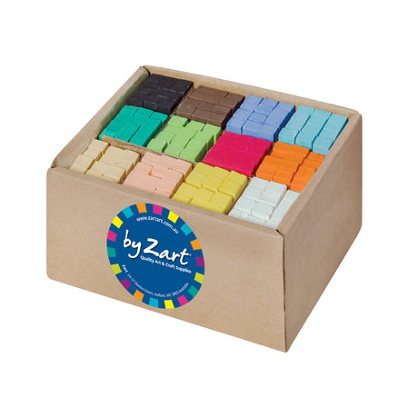A brown cardboard box of Zart Soft Pastels filled with square pastels sorted into colour sections, including black, brown, blue, teal, green, pink, orange, cream, peach, yellow and white. A round blue ‘by Zart’ label sits on the front against a white background.
