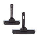 Two hard rubber rollers displayed side by side on a light grey background, featuring black cylindrical rollers mounted on metal frames. Each tool has a smooth black plastic handle with an oval hanging hole, showing subtle surface sheen and sturdy construction.