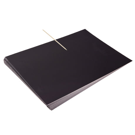 A stack of Zart Scratch Paper sheets in solid black, with a wooden stylus tool resting diagonally across the top sheet. The paper has a smooth, matte black surface, showing no visible texture or markings, ready for scratching designs into the surface.