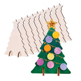 A row of Zart Wooden Standing Tree cut-outs in plain plywood, standing upright in a line and each topped with a small star. In front stands one decorated example painted green with a glittered gold star, gold string garlands and rows of round pastel and yellow discs.