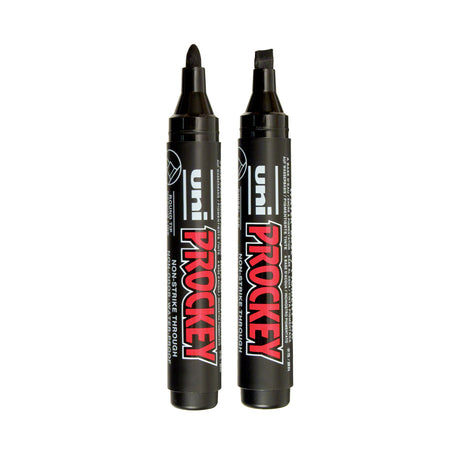 Two black Uni Prockey paint markers displayed upright against a pale grey background. One marker features a rounded bullet tip while the other has a broad chisel tip. Bold red and white “PROCKEY” branding contrasts against the matte black barrels with glossy black caps and detailing.