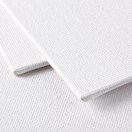 Close-up view of two white canvas boards stacked slightly offset. The woven canvas texture is clearly visible across the surface, with the top board lifted to reveal the firm board backing and clean wrapped edges. The surface shows a fine grid weave typical of primed canvas used for painting.