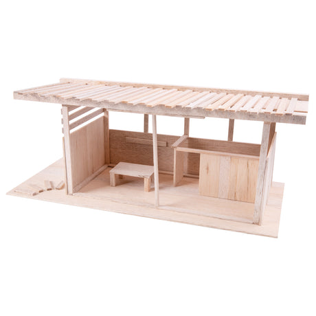 Lightweight balsa wood architectural model featuring a simple open structure with vertical posts, flat panels, and a slatted roof. Pale natural wood shows visible grain and soft, slightly fibrous texture. Clean, uniform colour highlights the material’s smooth cut edges and layered construction.
