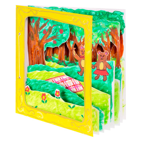 A sample artwork 3D diorama book made using Zart Card Squares White. Multiple layered card panels are painted in green and brown to create a forest scene with bear characters and a picnic rug. A yellow card outer frame with gold decorative border faces the viewer.