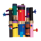 A group of colourful cylindrical cardboard tube artworks stand upright against a pale grey background. The tubes are decorated with bold blocks of colour including black, red, blue, yellow, purple and pink, with metallic gold corrugated bands, scalloped edges, geometric shapes and protruding decorative attachments.