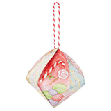 A decorated Zart Cardboard 3D Bauble painted with a Christmas confectionery theme, featuring a candy cane, striped lollipop, holly sprig, and pastel polka-dot sweets against wavy pink, cream, and blue icing patterns. Hung from a red and white twisted cord.