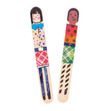 Two decorated Popstick Natural - Giant craft stick characters are displayed vertically against a pale grey background. The artworks feature hand-drawn faces, patterned washi tape clothing, metallic gold dots, colourful geometric designs, and painted striped legs with contrasting black shoes.