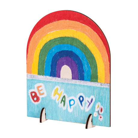 A hand-painted sample made using a Zart Desktop Message Board, showing a rainbow arching over a pale blue sky with the words "Be Happy" and a small floral sketch below. The arched wooden shape stands upright on its two side legs.