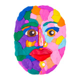 Close-up of a circular Plasticine face artwork made from overlapping pieces of brightly coloured Plasticine. The surface shows soft, smooth blending with subtle finger-pressed textures, combining bold colours such as purple, teal, pink, orange and yellow to create expressive facial features.