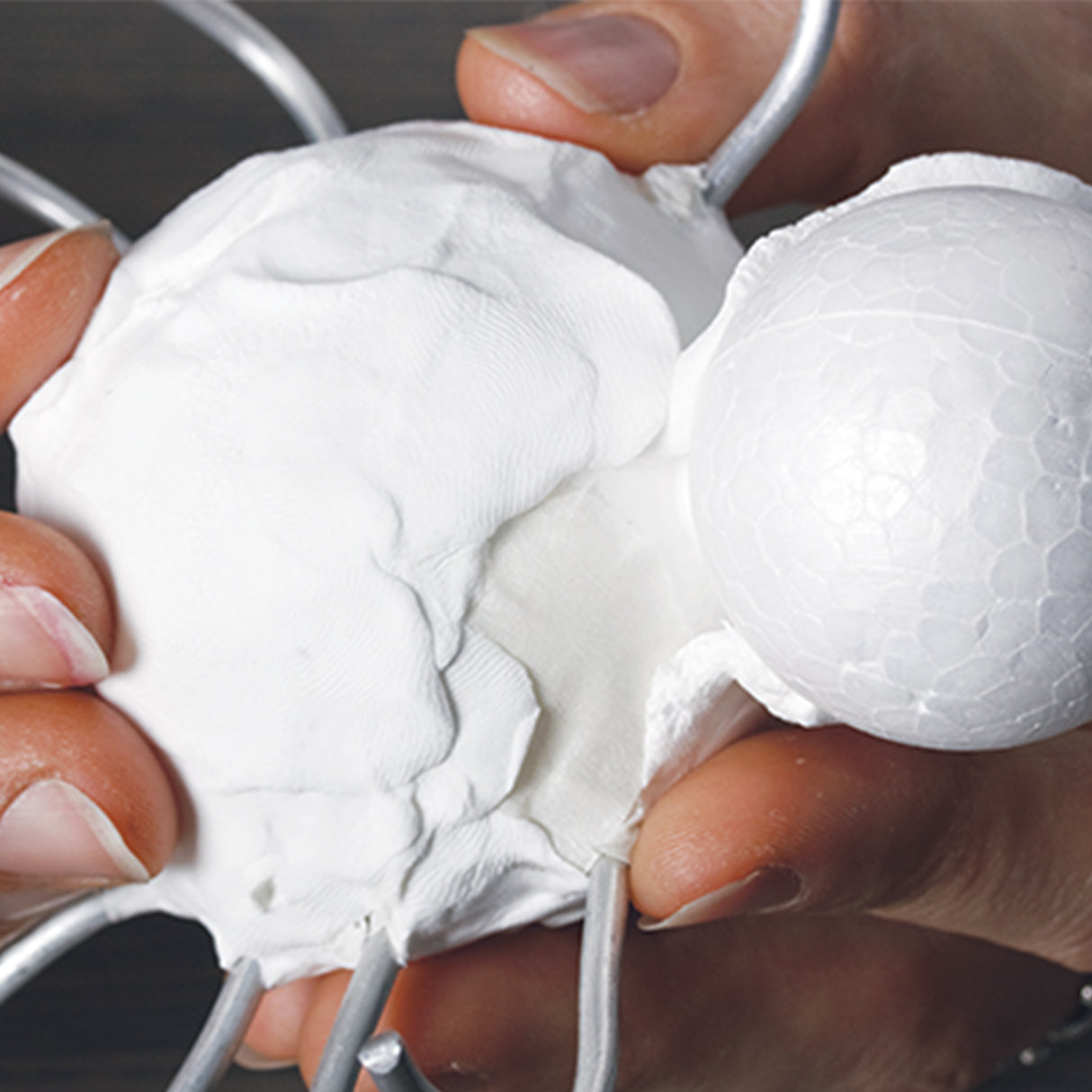 Hands shape white Paper Magiclay around wire and polystyrene armatures, showing pliability, smooth texture and suitability for sculptural construction.