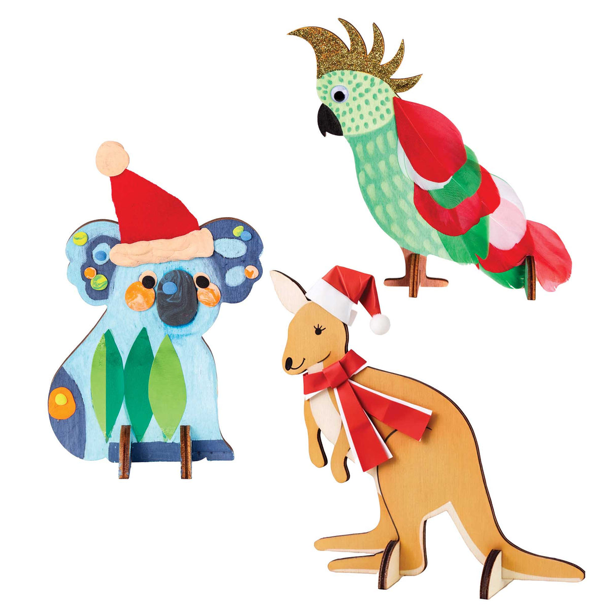 Three Zart Wooden Standing Australian Animals decorated as festive samples: a blue koala with painted spots wearing a red felt Santa hat, a cockatoo covered in real red, green and white feathers with a joggle eye, and a kangaroo painted golden-brown with a Santa hat and red ribbon scarf.