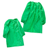 Two green Zart smocks laid out together, a smaller one in front and a larger one behind, showing the size difference between them. Both have an elasticated round neckline gathered into folds, long sleeves with elasticated cuffs, and a curved front hemline.