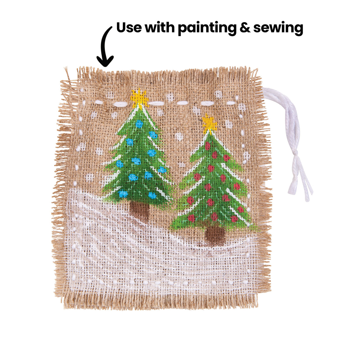 A square sample artwork on natural hessian fabric with frayed edges, decorated with a painted winter scene showing two green Christmas trees with yellow star toppers against a white snow ground and white dot details. An annotation reads "Use with painting & sewing" pointing to the fabric surface.