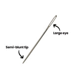 A single silver Zart tapestry needle shown diagonally, with two annotations. An arrow points to the long elongated eye at the upper end labelled ‘Large eye’, and a second arrow points to the lower end labelled ‘Semi-blunt tip’, where the shaft tapers to a rounded point.